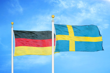 Germany and Sweden two flags on flagpoles and blue cloudy sky