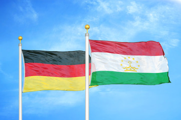 Germany and Tajikistan two flags on flagpoles and blue cloudy sky