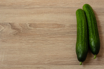 two juicy green cucumbers on a wooden table