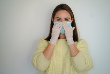 Happy smiling girl in sanitary gloves putting on medical face mask to protect herself from...