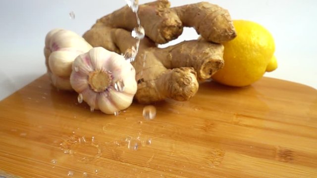 Juicy lemon, garlic and ginger on a carving wooden board. Slow motion. Alternative medicine.