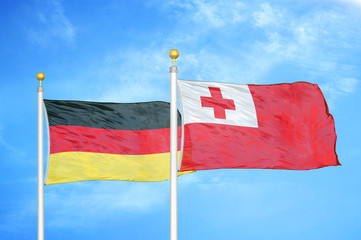 Germany and Tonga two flags on flagpoles and blue cloudy sky