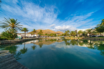 Fototapeta na wymiar Lake in the park and palm trees around with mountains on the horizon