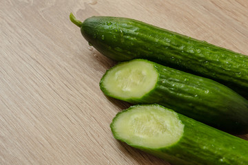 whole and sliced ​​juicy cucumbers on a wooden background