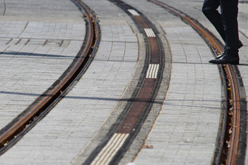 Close up of light rail train tracks. There is a man walking along the tracks. George street, Sydney city.