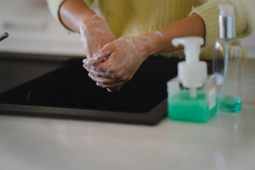 Crop picture of female hands washing with soap on her kitchen during the coronavirus pandemic, cleaning hands from viruses and bacterias with sanitizer detergent to protect health from infection