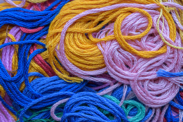 Multi-colored threads for the background. Colors - blue, pink, yellow. Randomly wriggle pattern. Concept of needlework, workshop.