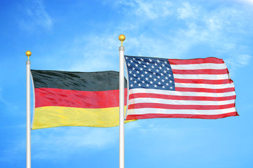 Germany and United States two flags on flagpoles and blue cloudy sky