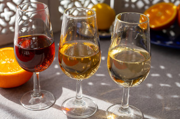 Glasses with cold dry fino and sweet cream sherry fortified wine and orange in sunlights, andalusian style interior on background