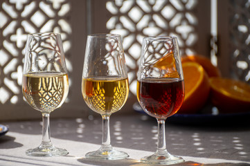 Glasses with cold dry fino and sweet cream sherry fortified wine in sunlights, andalusian style interior on background - obrazy, fototapety, plakaty