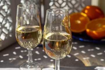 Glasses with cold fino sherry fortified wine and orange in sunlights, andalusian style interior on background