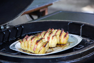 Cooking process. Preparation. Grilled potatoes with bacon and spices in a foil plate. Summer, picnic. Background image, copy space
