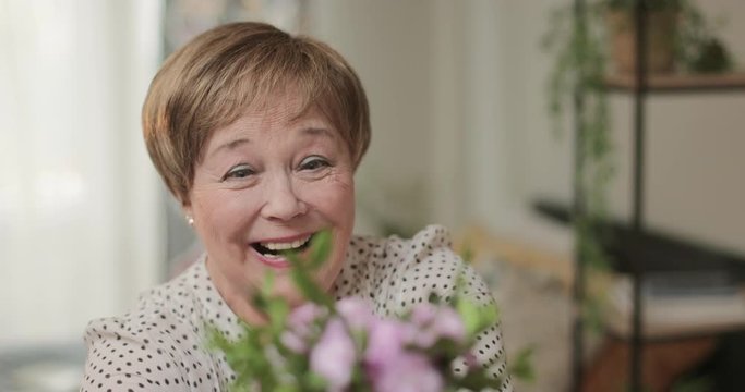 Close up view of emotional elderly woman getting flowers and smiling. Son giving bouquet to his mother.Concept of people and positive emotions.
