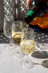 Pouring of cold fino sherry fortified wine in glass in sunlights, andalusian style interior on background