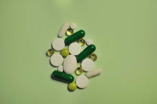 Different kind of pills on green table. Medicine against COVID-19 and diseases