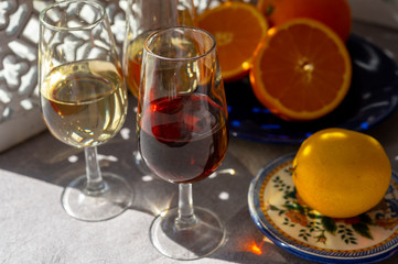 Glasses with cold dry fino and sweet cream sherry fortified wine and orange in sunlights, andalusian style interior on background