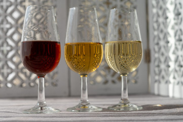 Glasses with cold dry fino and sweet cream sherry fortified wine in sunlights, andalusian style interior on background