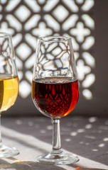 Glasses with cold dry fino and sweet cream sherry fortified wine in sunlights, andalusian style interior on background