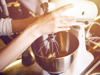 Fototapeta na wymiar Woman hands whipping with mixer. Making dessert in modern kitchen