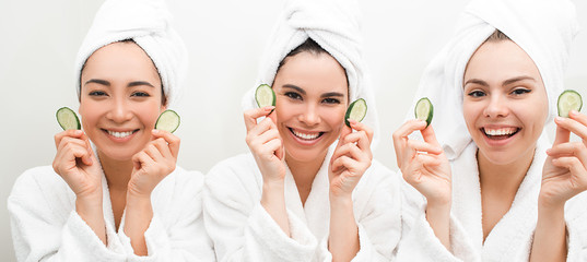 Super cucumber moisturizer face. Three beautiful women, with towels around head holding slices...