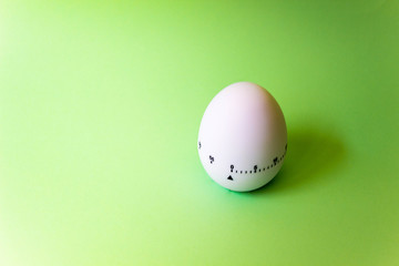 white egg timer on green background. Happy Easter in the kitchen. Home related, home staying. Free copy space.