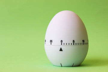white egg timer on green background. Happy Easter in the kitchen. Home related, home staying. Free copy space.
