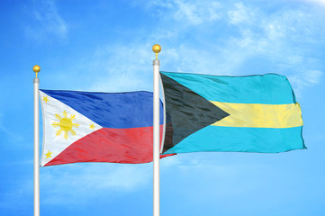 Philippines and Bahamas two flags on flagpoles and blue cloudy sky
