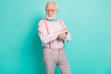 Photo of attractive serious grandpa prepare senior meeting party buttoning sleeve look side empty space wear specs pink shirt suspenders bow tie pants isolated teal color background