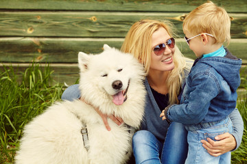 outdoor portrait mother, son and dog. child and mom walking samoyed laika.