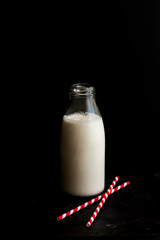 Vegan Cashew Milk in bottle with paper red straw on black surface