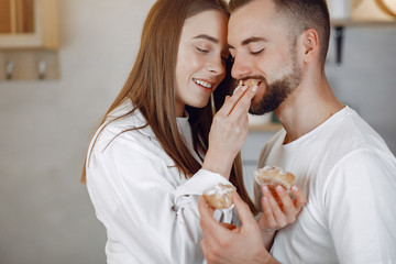 Cute couple in a kitchen. Lady in a white shirt. Pair at home