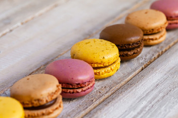Assortment of delicious traditional french macaroons. Colorful sweet dessert for real gourmands. Lemon, chocolate, caramel, raspberry flavors. Wooden rustic background, copy space, close up, macro