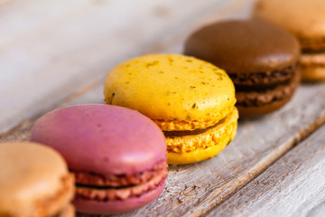 Assortment of delicious traditional french macaroons. Colorful sweet dessert for real gourmands. Lemon, chocolate, caramel, raspberry flavors. Wooden rustic background, copy space, close up, macro
