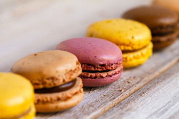 Assortment of delicious traditional french macaroons. Colorful sweet dessert for real gourmands. Lemon, chocolate, caramel, raspberry flavors. Wooden rustic background, copy space, close up, macro