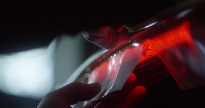 Hand cutting excess foil with a knife during the process of wrapping a car.