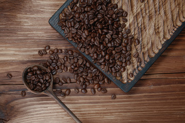 Wooden spoon with full coffee beans on a wooden table. Selective focus