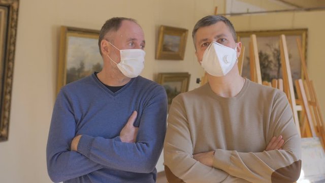 Introduction to art in the dark days of the pandemic. Two men look at and discuss a painting in an art gallery.