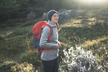 Beautiful smiling girl with a backpack spotted on a hiking trip in northern Norway. Situated in beautiful autumn landscape of Lofoten Islands. Picture shows leisure  outdoor activities.