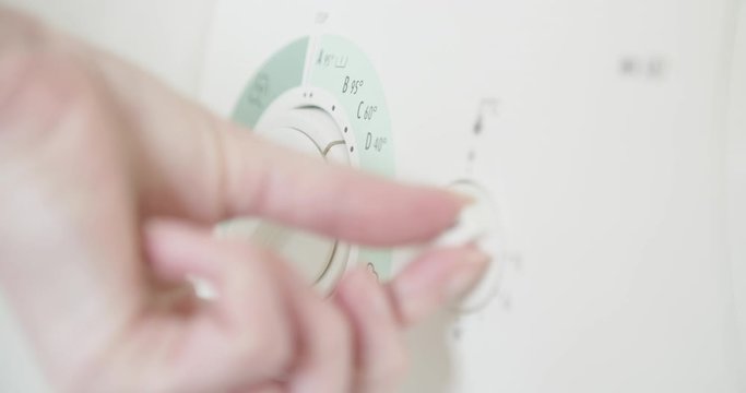 turning washing machine dials , female hand