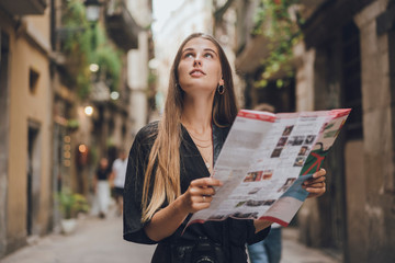 Beautiful tourist girl is walking around old city streets and looking for the sight seeing in the city guide and watching how gorgeous the streets look, concept of travelling and tourism
