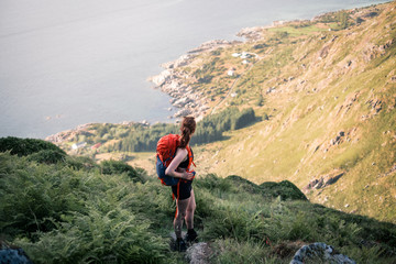Sexy mountain girl with a backpack spotted on a hiking trip in northern Norway. Situated in beautiful summer landscape and vegetation of Lofoten Islands. Picture shows leisure  outdoor activities. 
