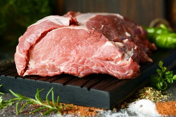 Fresh raw pork loin on the bone on a wooden board with herbs, spices and sea salt. meat for grilling. BBQ.A good piece of meat for cooking dinner.
