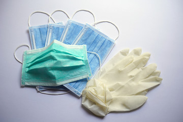 A green surgical face mask is slightly used, on top of blue.  Rubber gloves are all on white background.  Medical objects for Corona virus or Covid 19 protection. 