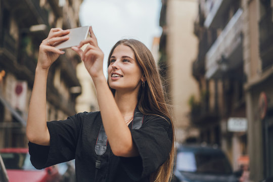 Young woman is talking by the video call on her phone and shows everything around to her friend. Video conferences are convenient for sharing your emotions with relatives while travelling.