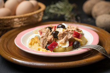 Potato salad with olives, tuna, boiled egg and its dressing. Delicious plate of Spanish food