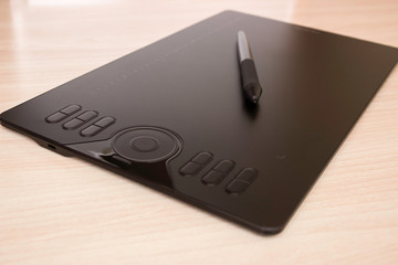 Graphic tablet and stylus with stylus stand on the table. Side view, tools for graphic drawing.