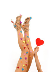 A pair of woman's legs are stretched out in a vertical form
in front of a white background. The model wears high heels
 and a pantyhose with multicolored butterflies on them.