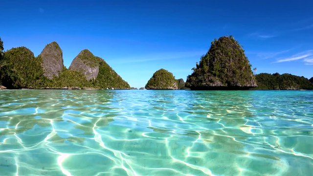 Crystal clear blue water in a tropical lagoon surrounded by limestone hills.
