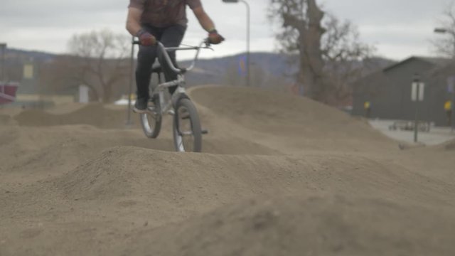 Slow motion bmx riders going fast at the dirt pumptrack at woodward, California. Steadicam cinematic camera movement.