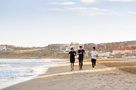 Three Young Boys Running Along The Beach